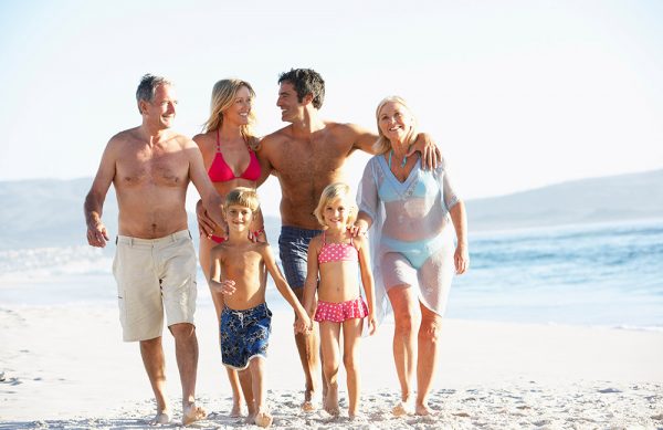 Three Generation Family On Holiday Walking Along Beach Three Generation Family On Holiday Walking Along Beach