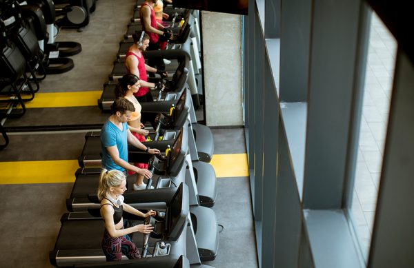 Top view at group of young people running on treadmills in modern gym